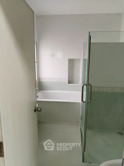 Modern bathroom with glass shower and bathtub in a minimalist design.