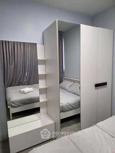 Modern bedroom with sleek wardrobe and mirror, featuring cozy bed and soft lighting for a tranquil ambiance.