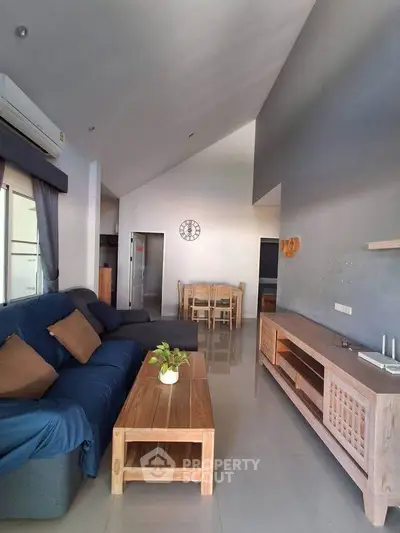 Spacious living room with modern furniture and high ceiling, perfect for relaxation and entertainment.