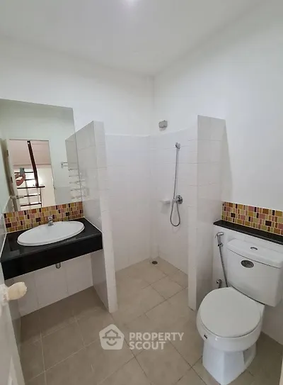 Modern bathroom with shower, toilet, and stylish sink in a tiled interior.