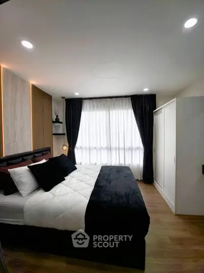 Modern bedroom with stylish decor, cozy bed, and ample natural light through large window.