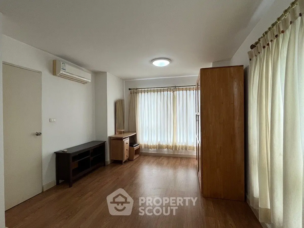 Spacious living room with wooden flooring and ample natural light in modern apartment.