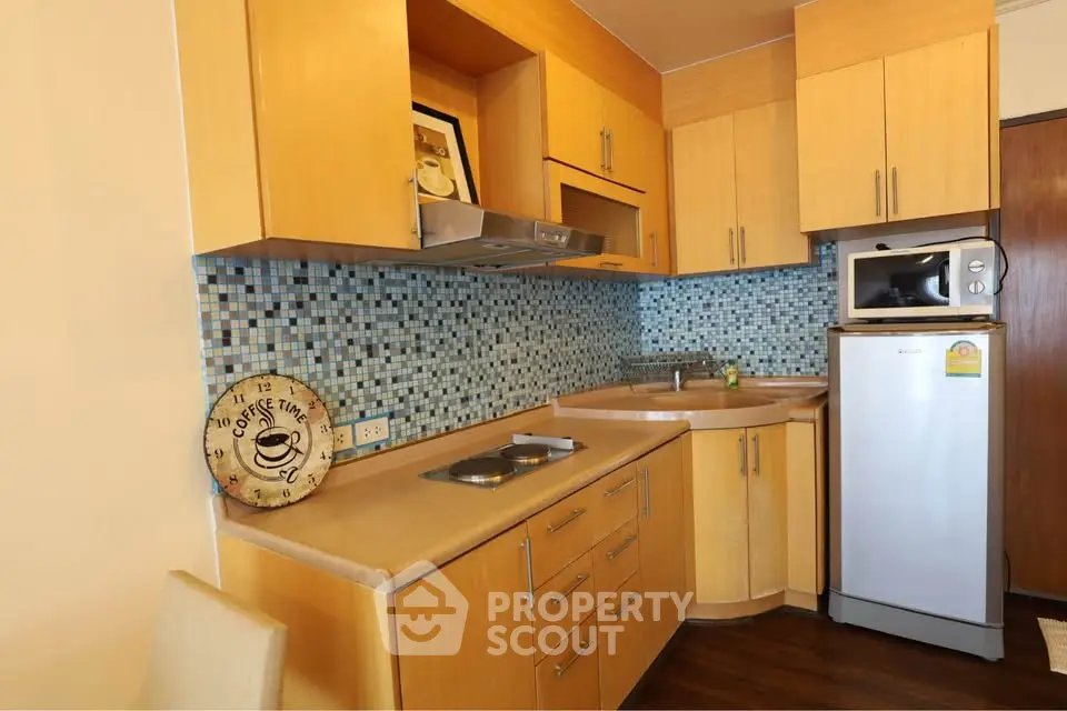 Charming kitchen with modern appliances and stylish backsplash in cozy apartment.