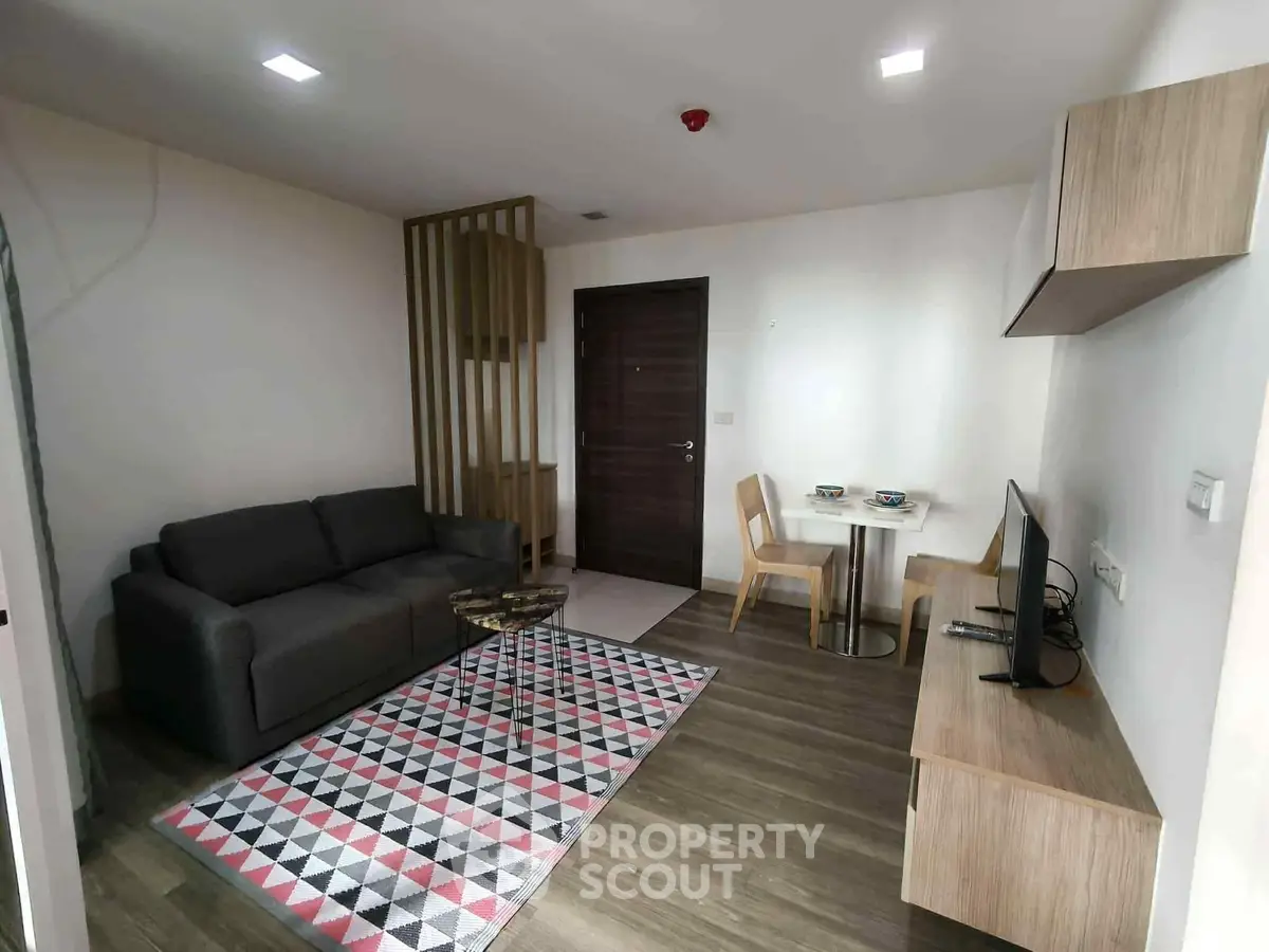 Modern living room with stylish furniture and geometric rug in a cozy apartment.