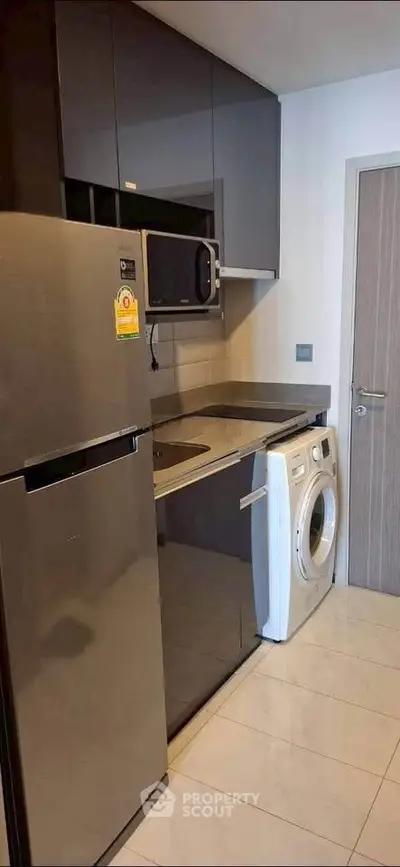 Modern compact kitchen with stainless steel appliances and washing machine