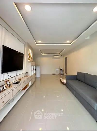 Spacious modern living room with sleek design and large TV, perfect for relaxation.