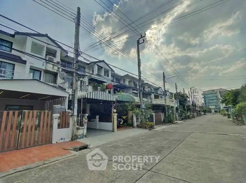 Charming townhouse street view with lush greenery and clear sky, perfect for serene living.