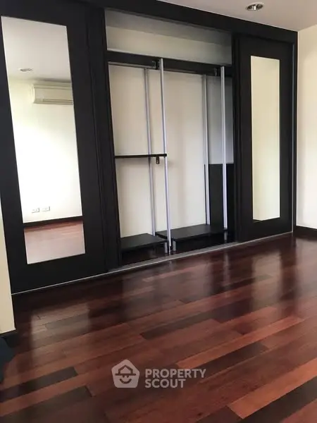 Spacious room with elegant wooden flooring and built-in closet, perfect for modern living.