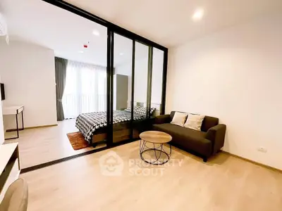 Modern studio apartment with glass partition, cozy living area, and stylish bedroom.