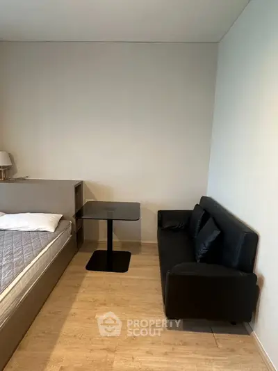 Modern studio apartment with cozy bed and sleek black sofa, perfect for urban living.