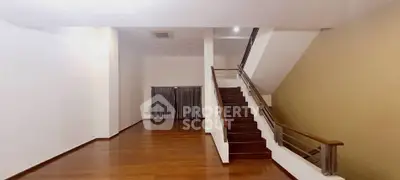 Spacious modern living room with elegant wooden staircase and sleek flooring.