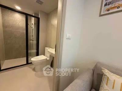 Modern bathroom with glass shower and adjacent cozy living area.