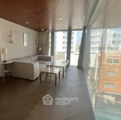 Modern living room with floor-to-ceiling windows and city view, featuring elegant furniture and wooden ceiling.