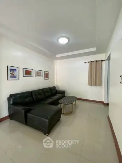 Spacious living room with modern black leather sofa and elegant decor.