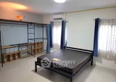 Spacious bedroom with modern metal bed frame and ample natural light, perfect for comfortable living.