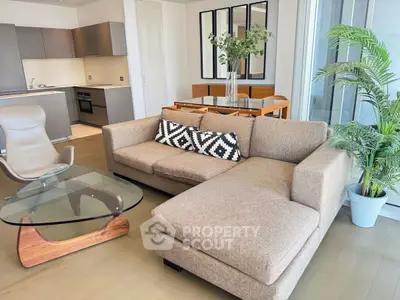 Modern living room with stylish furniture and open kitchen layout, featuring a cozy sectional sofa and elegant decor.