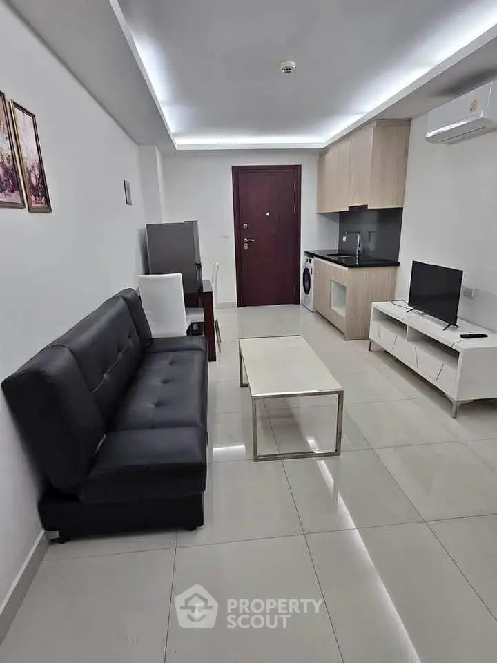 Modern living room with sleek furniture and compact kitchen area, perfect for urban living.