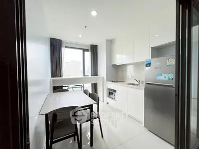 Modern kitchen with sleek white cabinets and dining area, featuring city view from window.