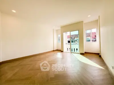 Spacious empty room with wooden flooring and large windows for natural light