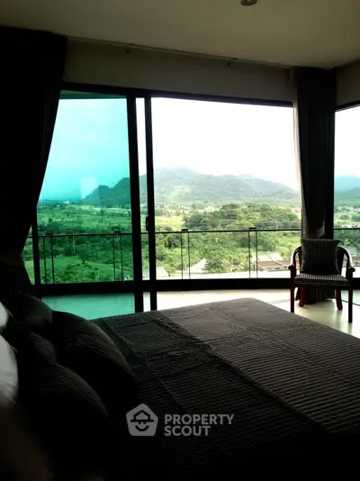 Spacious bedroom with floor-to-ceiling windows offering panoramic mountain views, seamlessly blending indoor comfort with the beauty of nature.