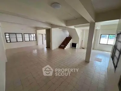 Spacious open-plan interior with tiled flooring and staircase, ideal for customization.