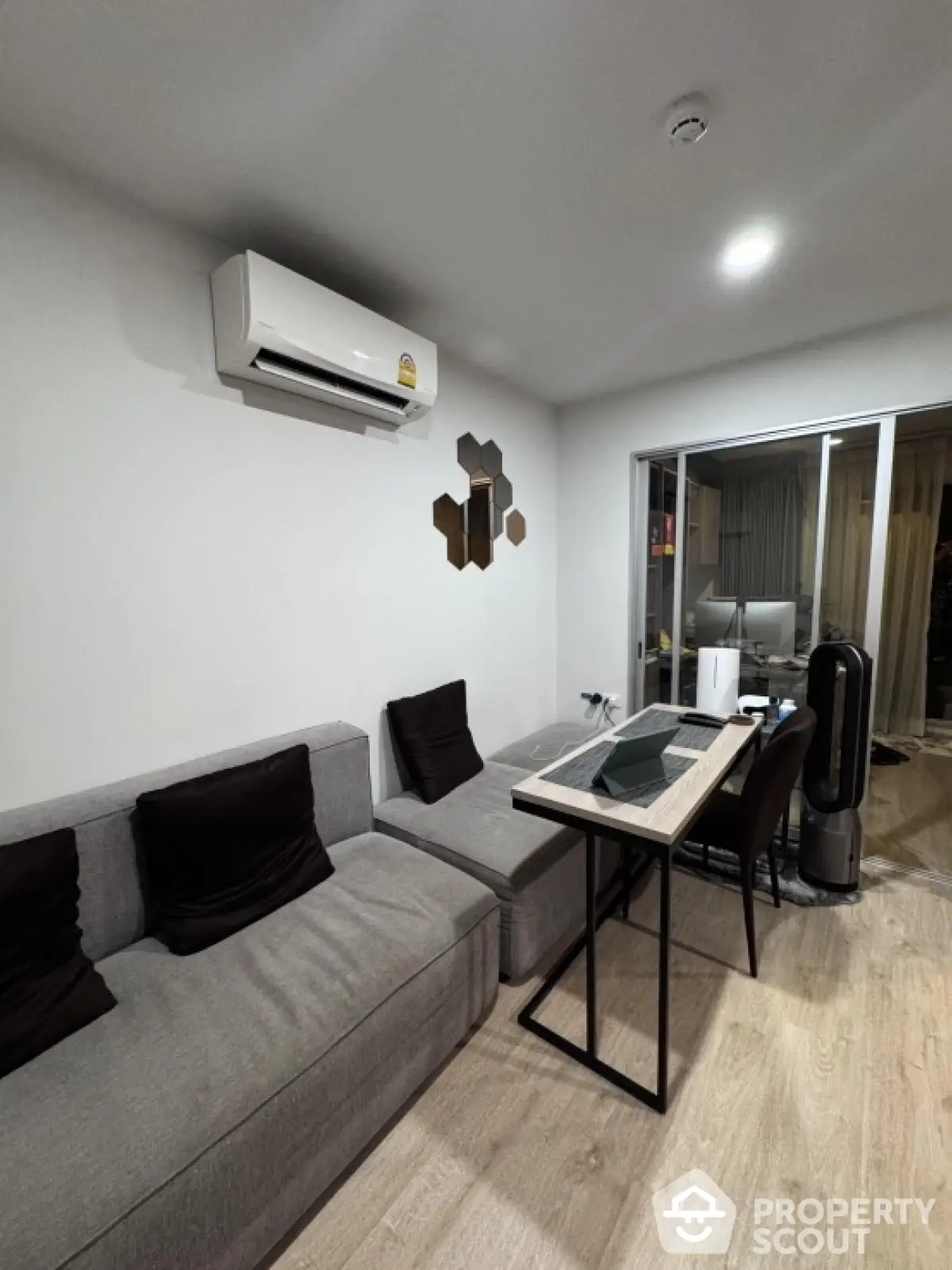 Modern living room with sleek furniture and air conditioning, featuring a cozy workspace.