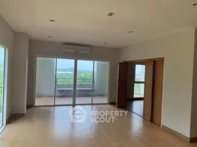 Spacious living room with large windows and balcony offering scenic views.
