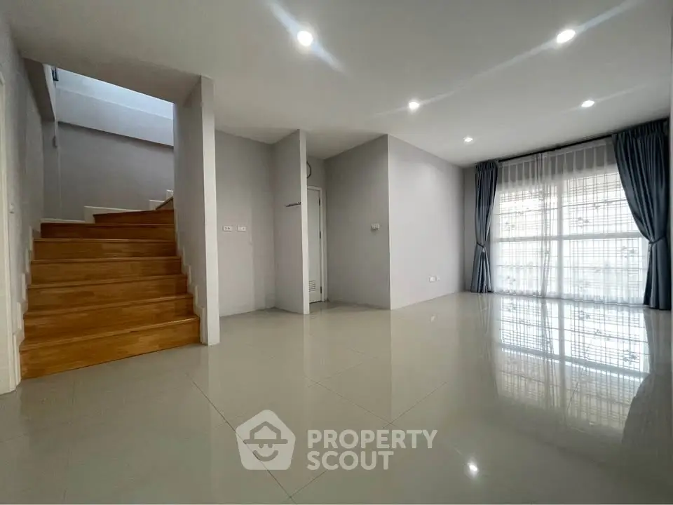 Spacious modern living room with wooden staircase and large windows