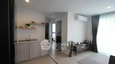 Modern open-plan living room with kitchen, featuring sleek design and natural light.