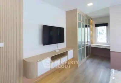 Modern living room with sleek TV unit and large window for natural light.