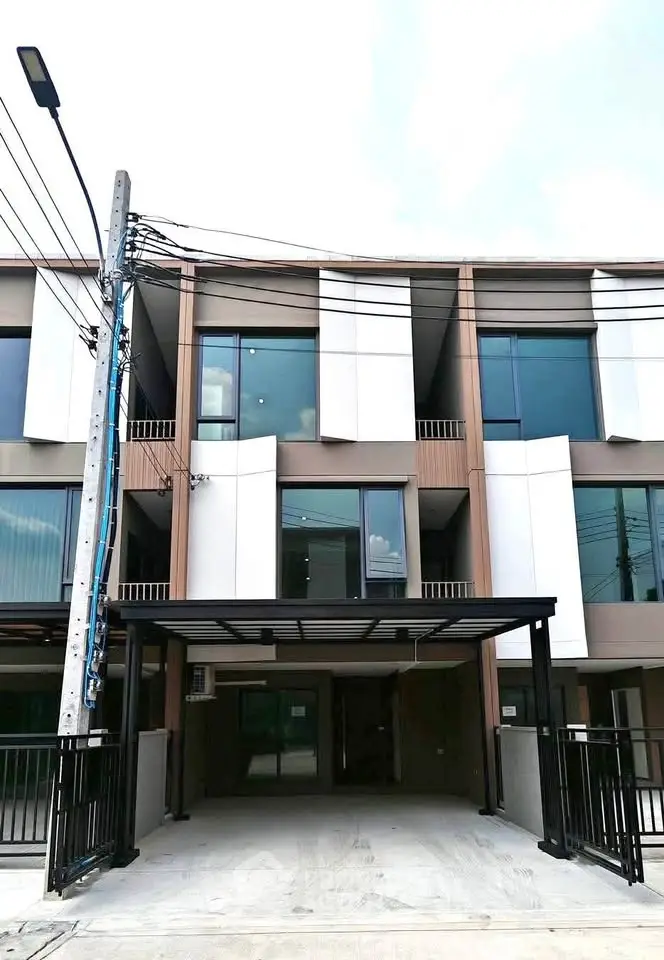 Modern three-story townhouse with sleek facade and large windows, offering contemporary urban living.