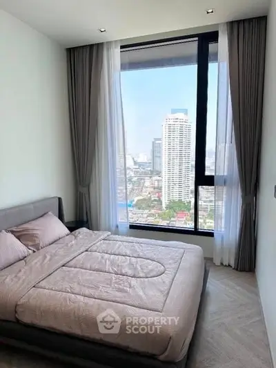 Modern bedroom with large window offering stunning city view in high-rise apartment.