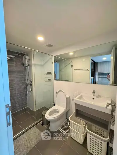 Modern bathroom with glass shower, sleek fixtures, and ample storage space.