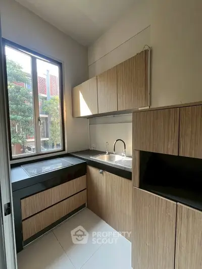 Modern kitchen with sleek cabinetry and large window for natural light