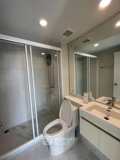 Modern bathroom with glass shower and sleek fixtures in a contemporary home.