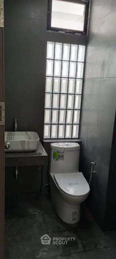 Modern bathroom with sleek design and glass block window for natural light.