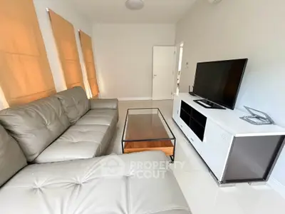 Modern living room with sleek leather sofas and large TV unit, perfect for relaxation and entertainment.