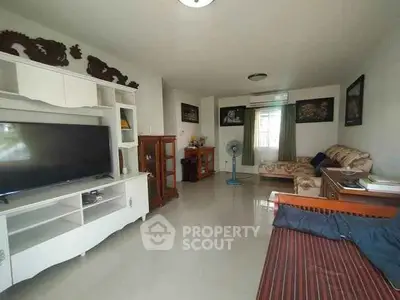 Spacious living room with modern decor and large TV, perfect for relaxation.
