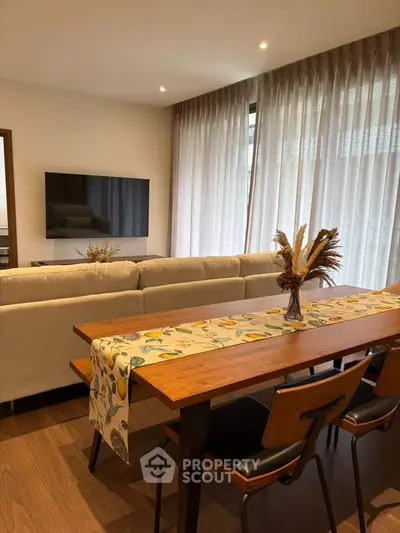Modern living room with elegant dining area and cozy seating, featuring stylish decor and natural light.