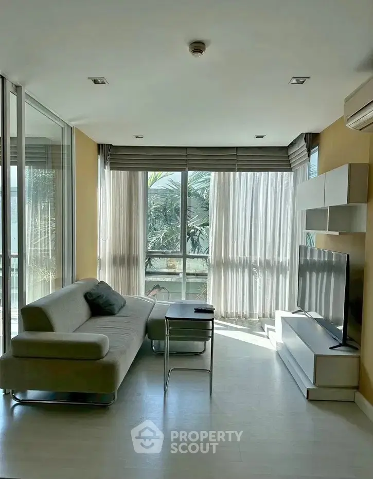 Modern living room with large windows and stylish furniture, offering a bright and inviting atmosphere.