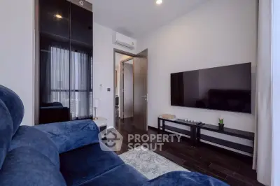 Modern living room with sleek furniture and wall-mounted TV, featuring dark wood flooring and elegant decor.