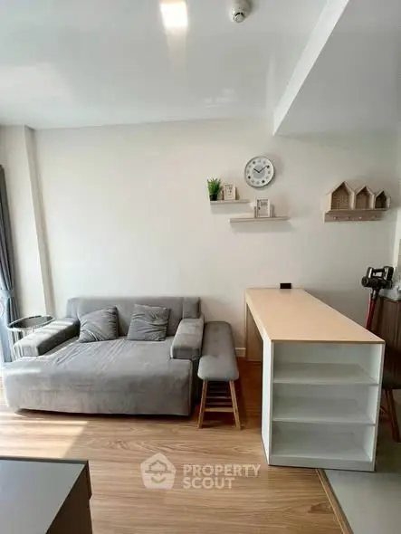 Modern living room with stylish gray sofa and wooden flooring, featuring minimalist decor and natural light.