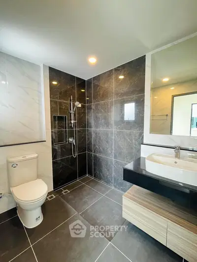 Modern bathroom with sleek design, featuring a shower and stylish sink area.