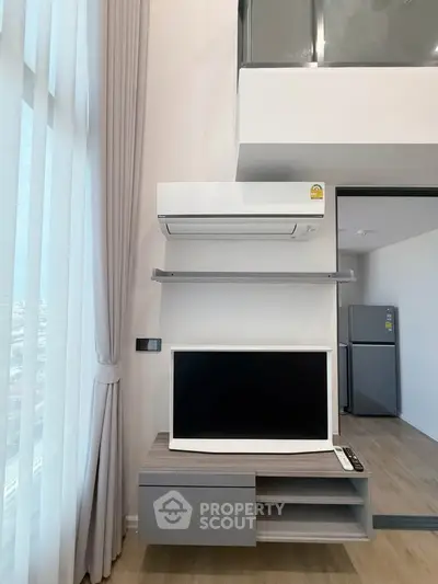 Modern living room with air conditioner, TV, and sleek furniture in a stylish apartment.