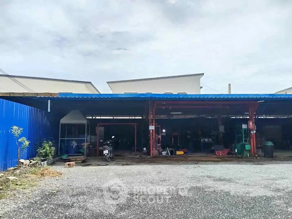 Spacious industrial property with ample parking and covered work area, ideal for automotive or storage use.