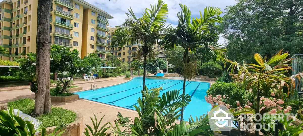 Lush tropical oasis with a sparkling pool nestled within a modern residential complex, surrounded by vibrant flora and well-manicured gardens.