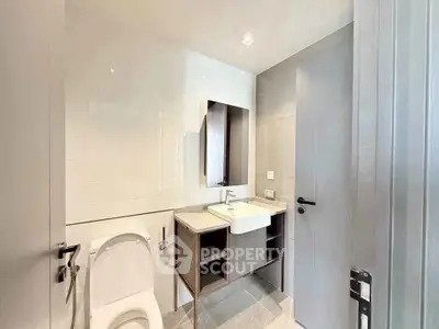 Modern bathroom with sleek fixtures and minimalist design, featuring a wall-mounted sink and toilet.