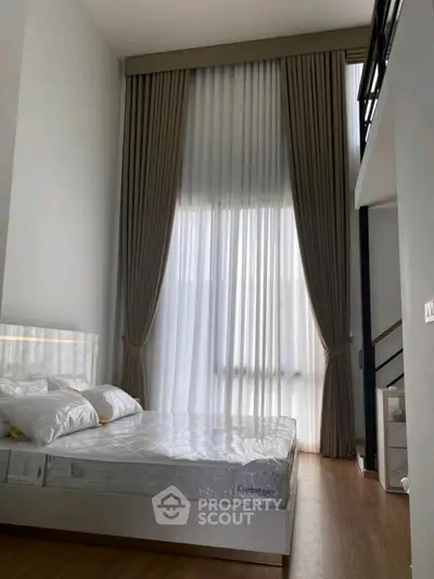 Modern bedroom with high ceiling and elegant curtains in a stylish apartment.