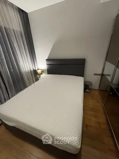 Cozy bedroom with modern design, featuring a comfortable bed and stylish mirrored wardrobe.