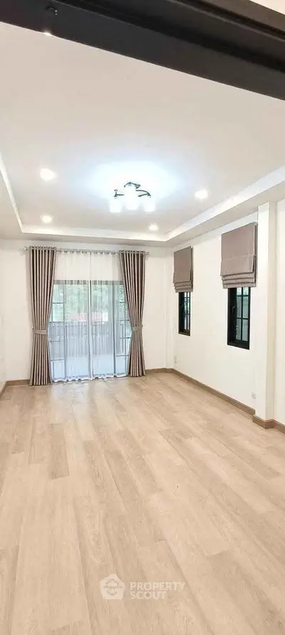 Spacious living room with elegant wooden flooring and large windows for natural light.